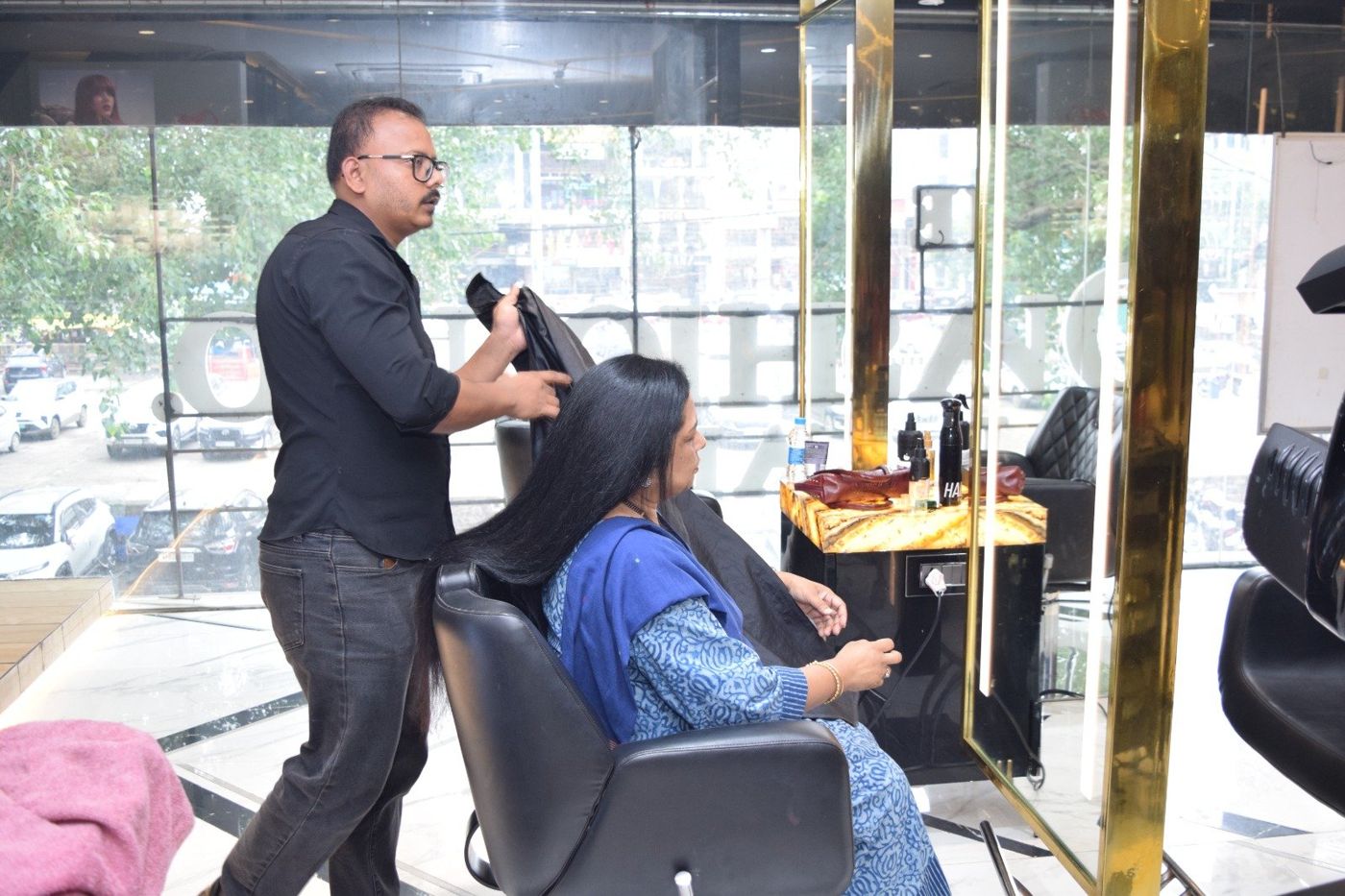 A stylist preparing a client in a black leather chair at The Fashion Co.